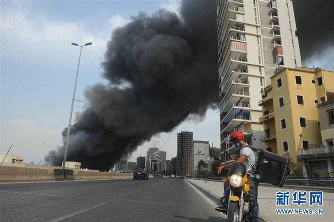 9月10日，在黎巴嫩首都贝鲁特，一名外卖快递员准备用手机拍摄港口区一处仓库起火后产生的浓烟。