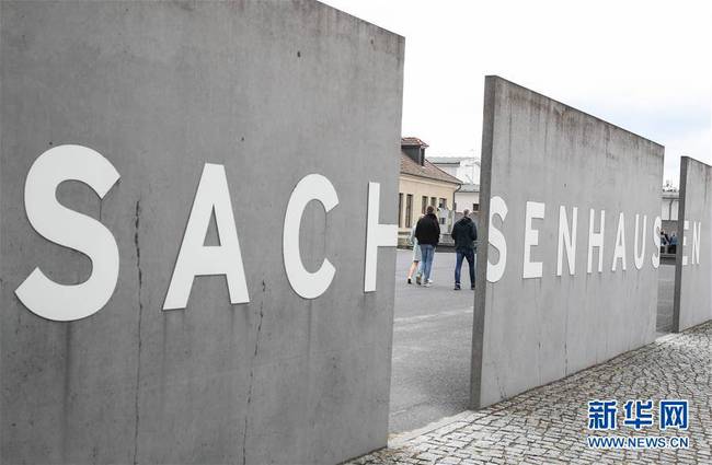 这是8月27日，在德国柏林以北的小城奥拉宁堡，参观者经过萨克森豪森集中营遗址纪念馆的入口处。