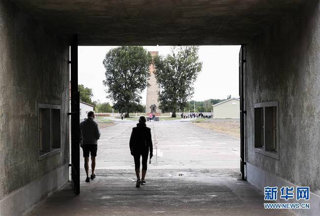 这是8月27日，在德国柏林以北的小城奥拉宁堡，两名参观者经过铁门进入萨克森豪森集中营营区。 
