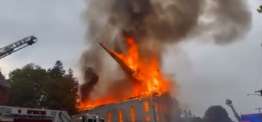 美国一教堂疑遭雷击后烧毁：尖塔在熊熊大火中倾倒，砸塌低矮建筑